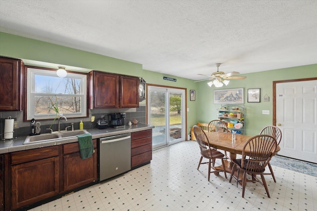 kitchen featuring ceiling fan, tile countertops, light floors, stainless steel dishwasher, and a sink