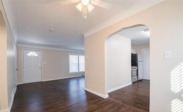 foyer with arched walkways, dark wood finished floors, baseboards, and ceiling fan