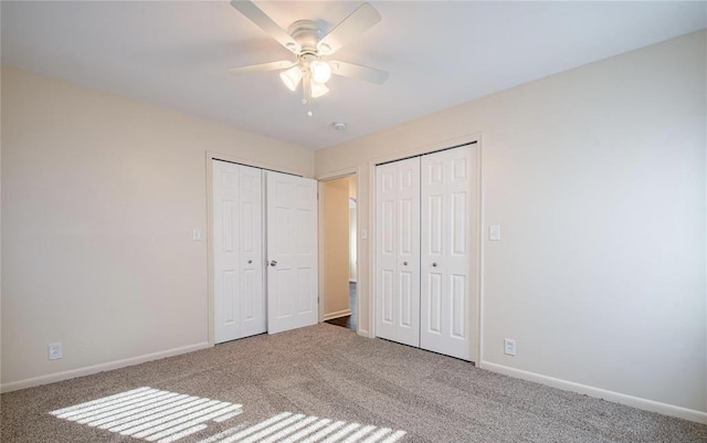 unfurnished bedroom featuring a ceiling fan, baseboards, multiple closets, and carpet floors