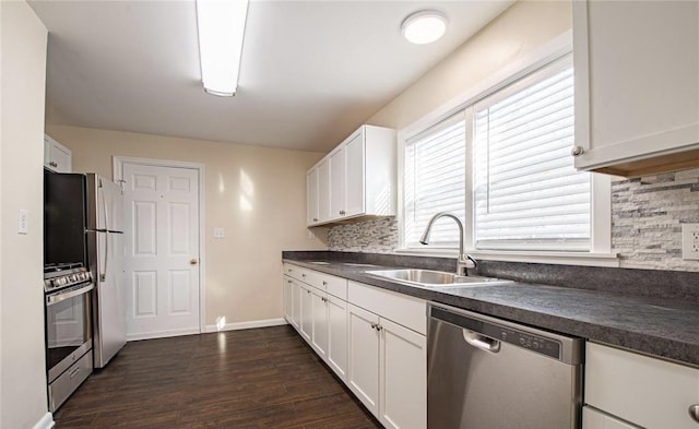 kitchen featuring dark wood-style flooring, a sink, white cabinets, appliances with stainless steel finishes, and dark countertops