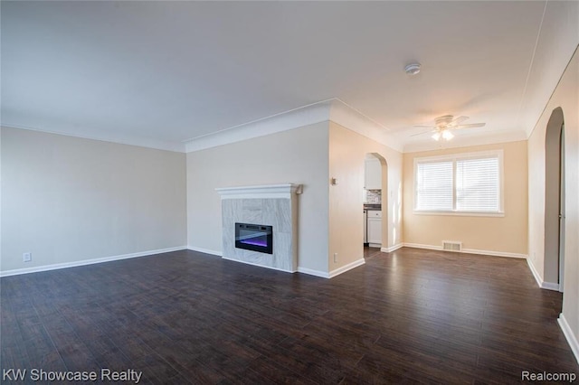 unfurnished living room featuring a ceiling fan, visible vents, arched walkways, ornamental molding, and dark wood-type flooring