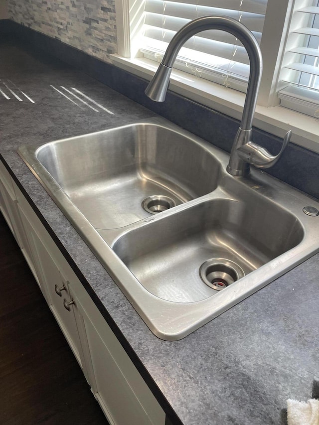 details with a sink, backsplash, dark countertops, and white cabinets