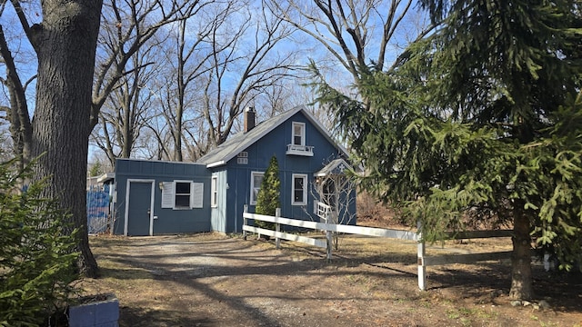 view of front of home featuring an outdoor structure, fence, driveway, and a chimney