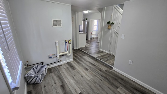 hallway featuring wood finished floors, visible vents, and baseboards