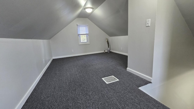 additional living space featuring visible vents, baseboards, lofted ceiling, and dark colored carpet