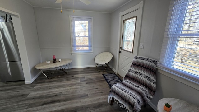 sitting room with ornamental molding, wood finished floors, baseboards, and ceiling fan