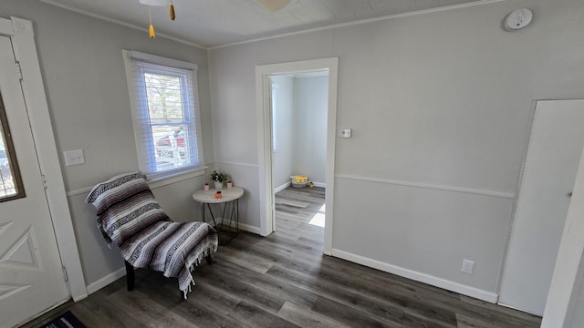 living area with baseboards, wood finished floors, a ceiling fan, and crown molding