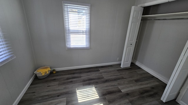 unfurnished bedroom with wood finished floors, baseboards, and a closet