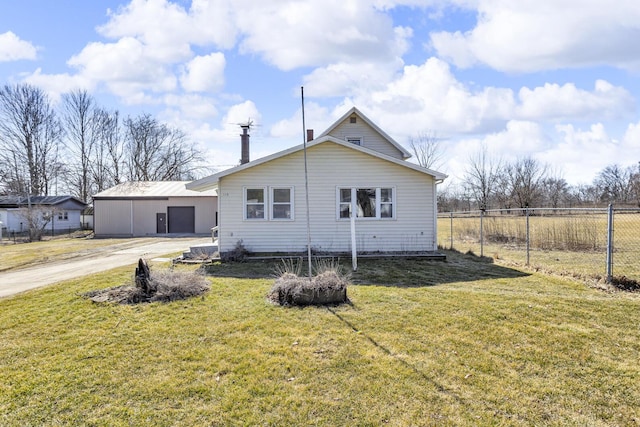 rear view of house featuring a garage, fence, a lawn, and driveway