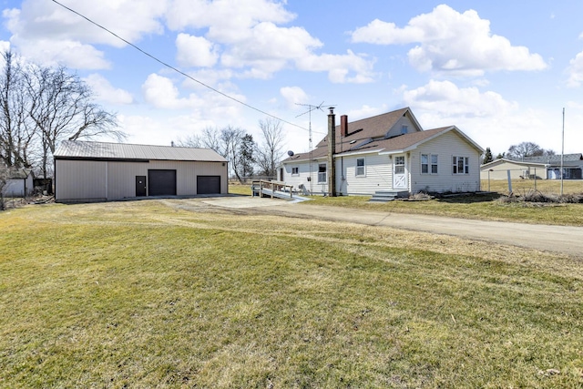 view of yard featuring a garage, driveway, and an outdoor structure