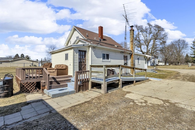 back of property featuring a wooden deck and a chimney