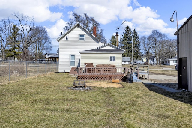 back of house with a chimney, a lawn, a wooden deck, and fence