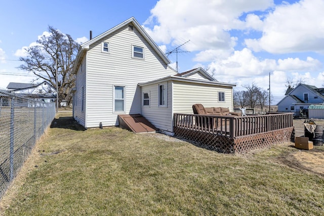 rear view of house with a lawn, a wooden deck, and fence