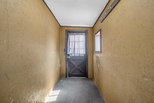 doorway featuring carpet flooring and a textured wall