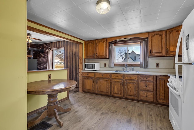 kitchen with white appliances, plenty of natural light, brown cabinetry, and light wood finished floors