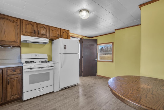 kitchen with light wood-type flooring, under cabinet range hood, white appliances, brown cabinetry, and light countertops