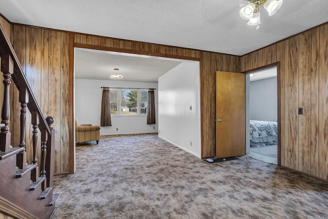 interior space with stairs, wooden walls, carpet, and a textured ceiling