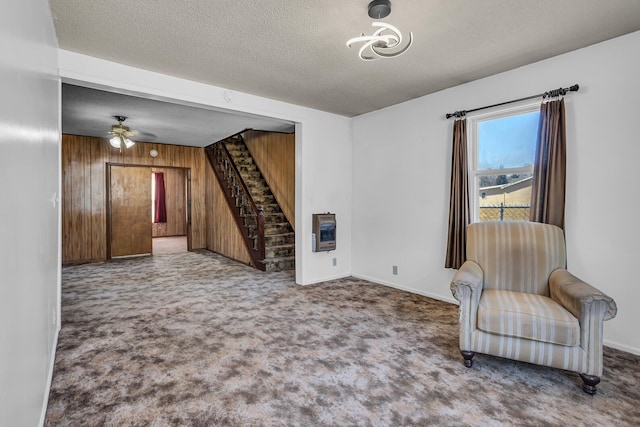 living area with heating unit, wooden walls, stairs, and carpet floors