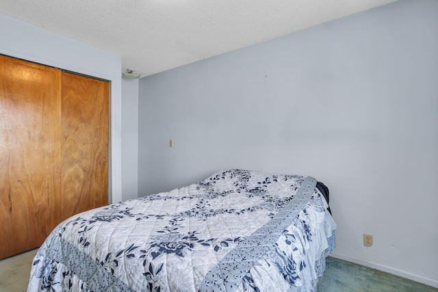 carpeted bedroom featuring a closet, a textured ceiling, and baseboards