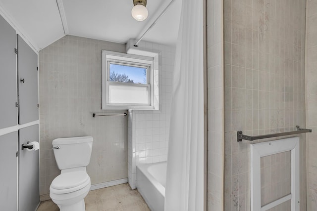 full bathroom with lofted ceiling, toilet, and tile walls