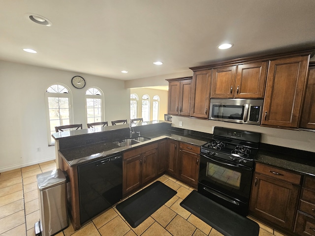 kitchen featuring black appliances, a healthy amount of sunlight, a peninsula, and a sink