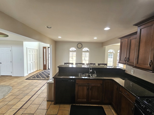 kitchen featuring dark brown cabinetry, a peninsula, black appliances, and a sink