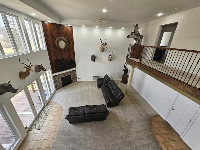 carpeted living room with recessed lighting, a stone fireplace, and a ceiling fan