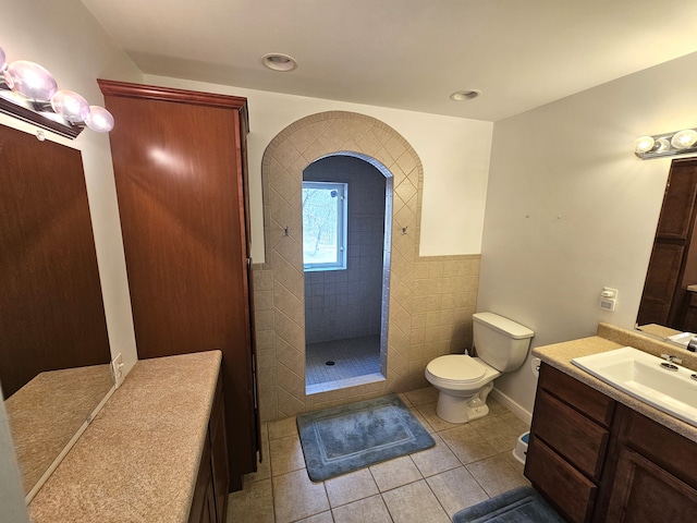 bathroom with tile patterned floors, tiled shower, toilet, and vanity