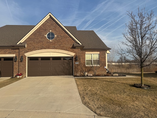 view of front of house with a front yard, brick siding, driveway, and a shingled roof