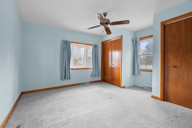 unfurnished bedroom with visible vents, multiple windows, baseboards, and carpet floors