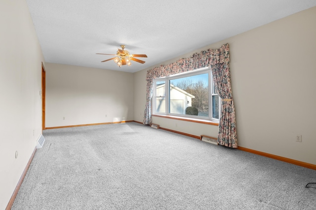 carpeted empty room with visible vents, baseboards, a textured ceiling, and ceiling fan