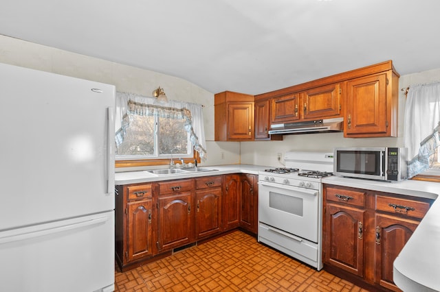 kitchen with white appliances, light countertops, under cabinet range hood, and a sink