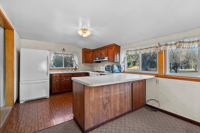 kitchen featuring white appliances, baseboards, a peninsula, light countertops, and under cabinet range hood