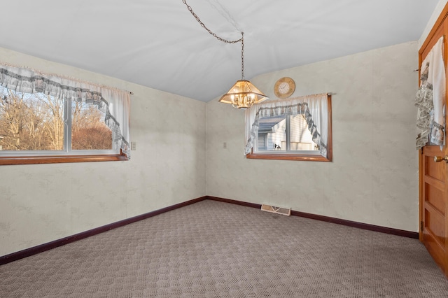 empty room featuring visible vents, carpet, a healthy amount of sunlight, and an inviting chandelier