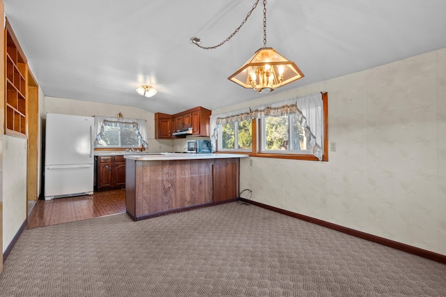 kitchen featuring an inviting chandelier, freestanding refrigerator, light countertops, vaulted ceiling, and dark carpet