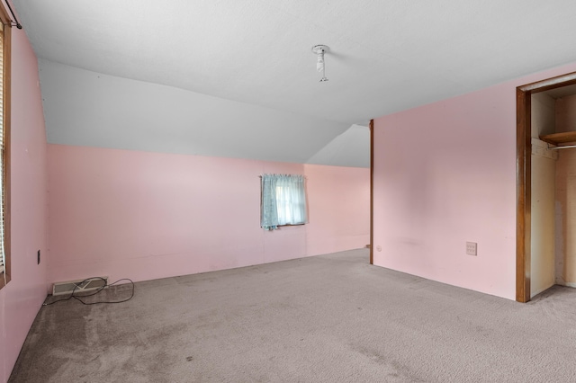 additional living space featuring lofted ceiling and carpet flooring