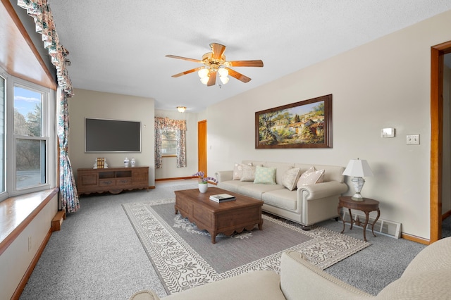 carpeted living area with visible vents, baseboards, a textured ceiling, and a ceiling fan