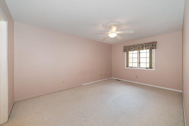 spare room featuring light carpet, visible vents, baseboards, and ceiling fan