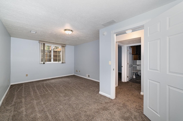 empty room with visible vents, baseboards, dark carpet, and a textured ceiling