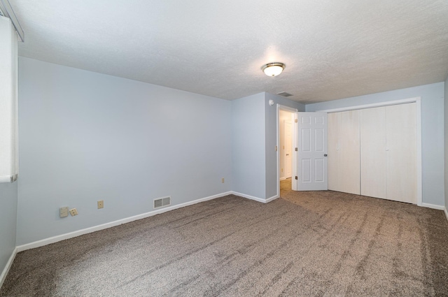 unfurnished bedroom featuring visible vents, carpet floors, a textured ceiling, and baseboards