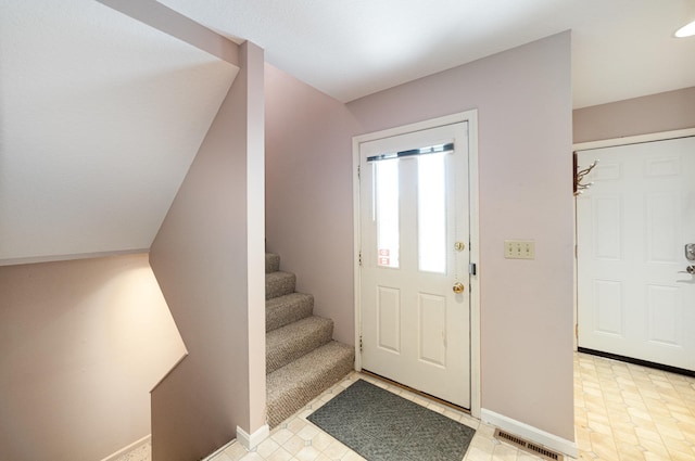 foyer entrance with stairway, baseboards, and visible vents