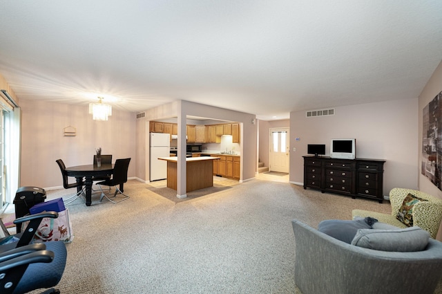 living area with visible vents, light colored carpet, and baseboards