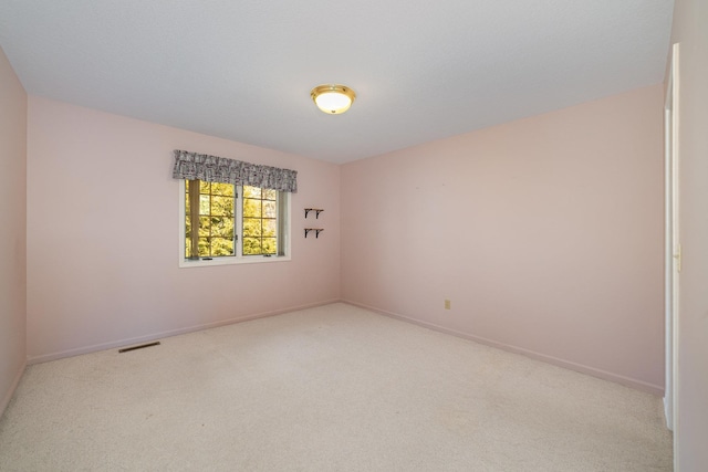 spare room with carpet flooring, baseboards, and visible vents