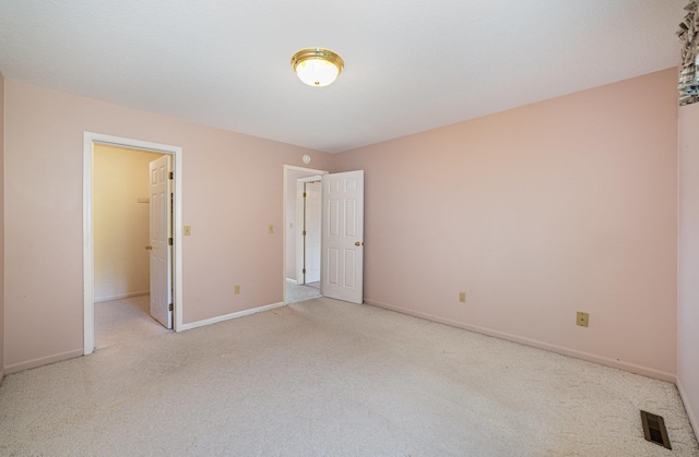 unfurnished bedroom featuring visible vents, carpet floors, baseboards, and a spacious closet