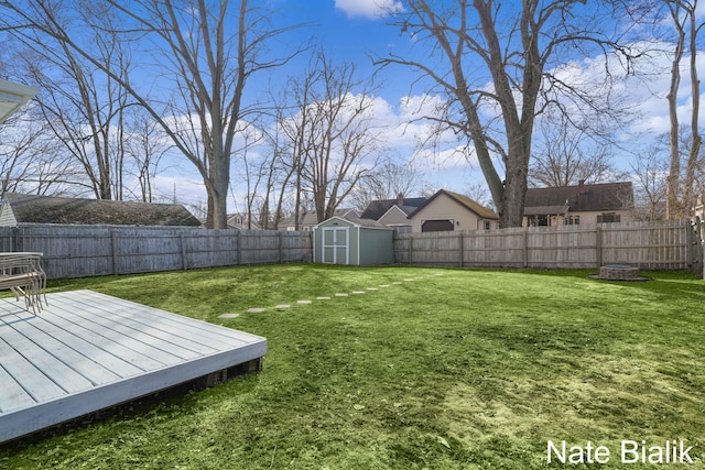 view of yard with an outdoor structure, a fenced backyard, a shed, and a wooden deck