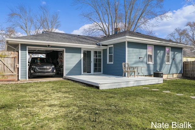 rear view of house featuring fence, a yard, an attached garage, a wooden deck, and a chimney