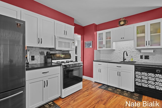 kitchen featuring white microwave, light wood-style flooring, freestanding refrigerator, dishwasher, and gas range