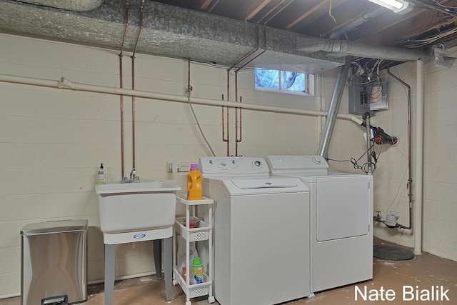 clothes washing area featuring electric panel, washing machine and dryer, laundry area, and a sink