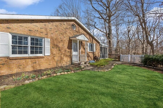 view of front facade featuring a front lawn, fence, and brick siding