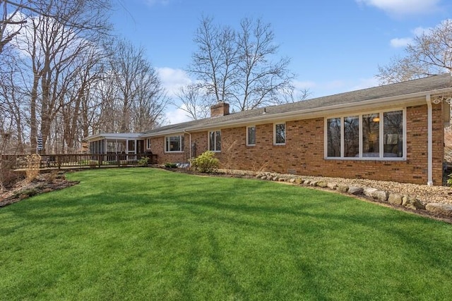 back of property with brick siding, a lawn, a chimney, and a sunroom